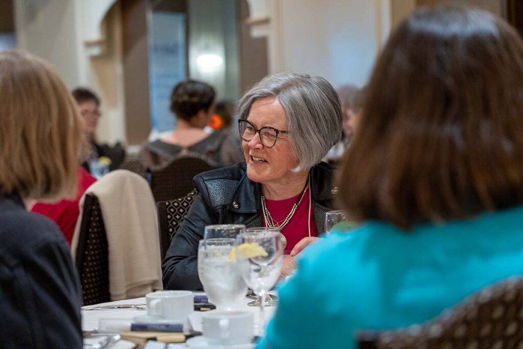 she shares member smiling at table